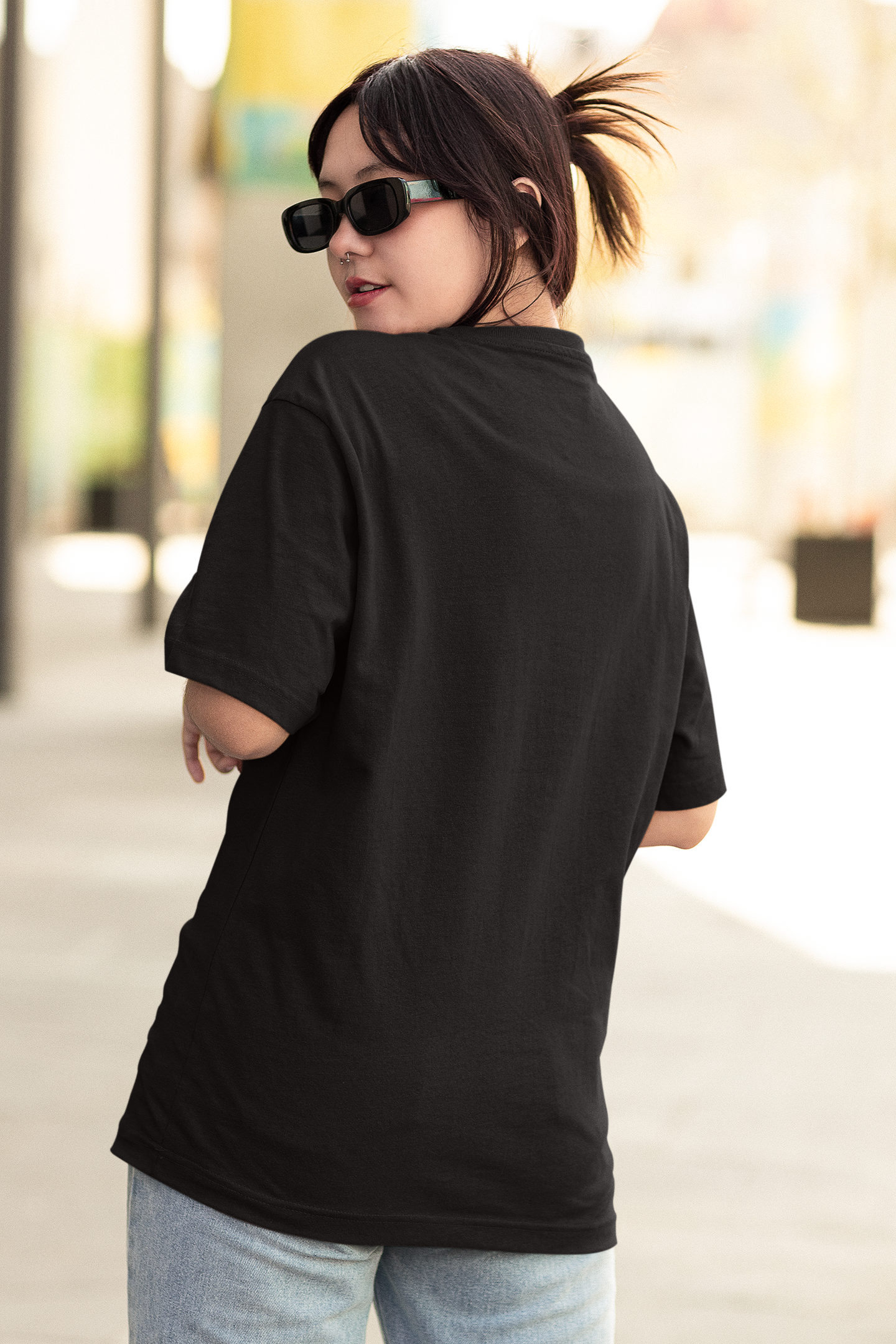 Back view of female model wearing a black oversized t-shirt featuring a stylish design inspired by Blackpink member Jennie. Ideal for fans of Jennie, Blackpink, and K-Pop music enthusiasts interested in idol fashion.