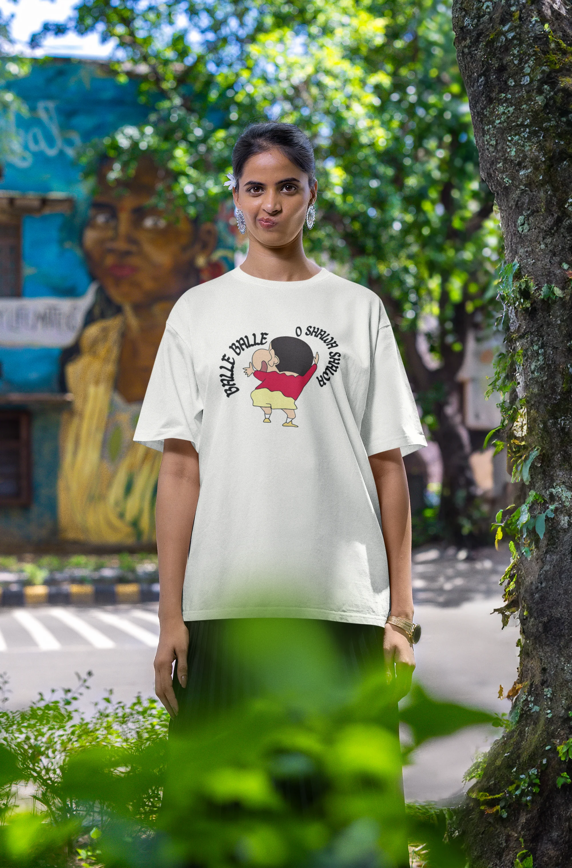 Third front view of female model wearing an oversized off-white tee with Shinchan dancing and the text "Balle Balle". A perfect blend of anime and Bollywood for Shinchan fans.