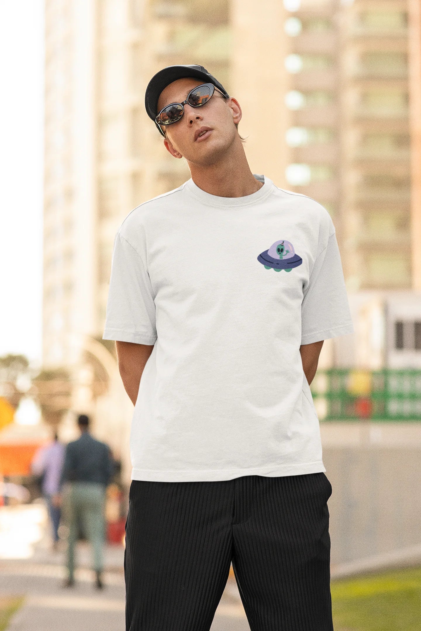 Second front view of a male model wearing a off-white oversized t-shirt featuring a fun "Alienated" design with elements of spaceships, UFOs, and a hint of extraterrestrial life.