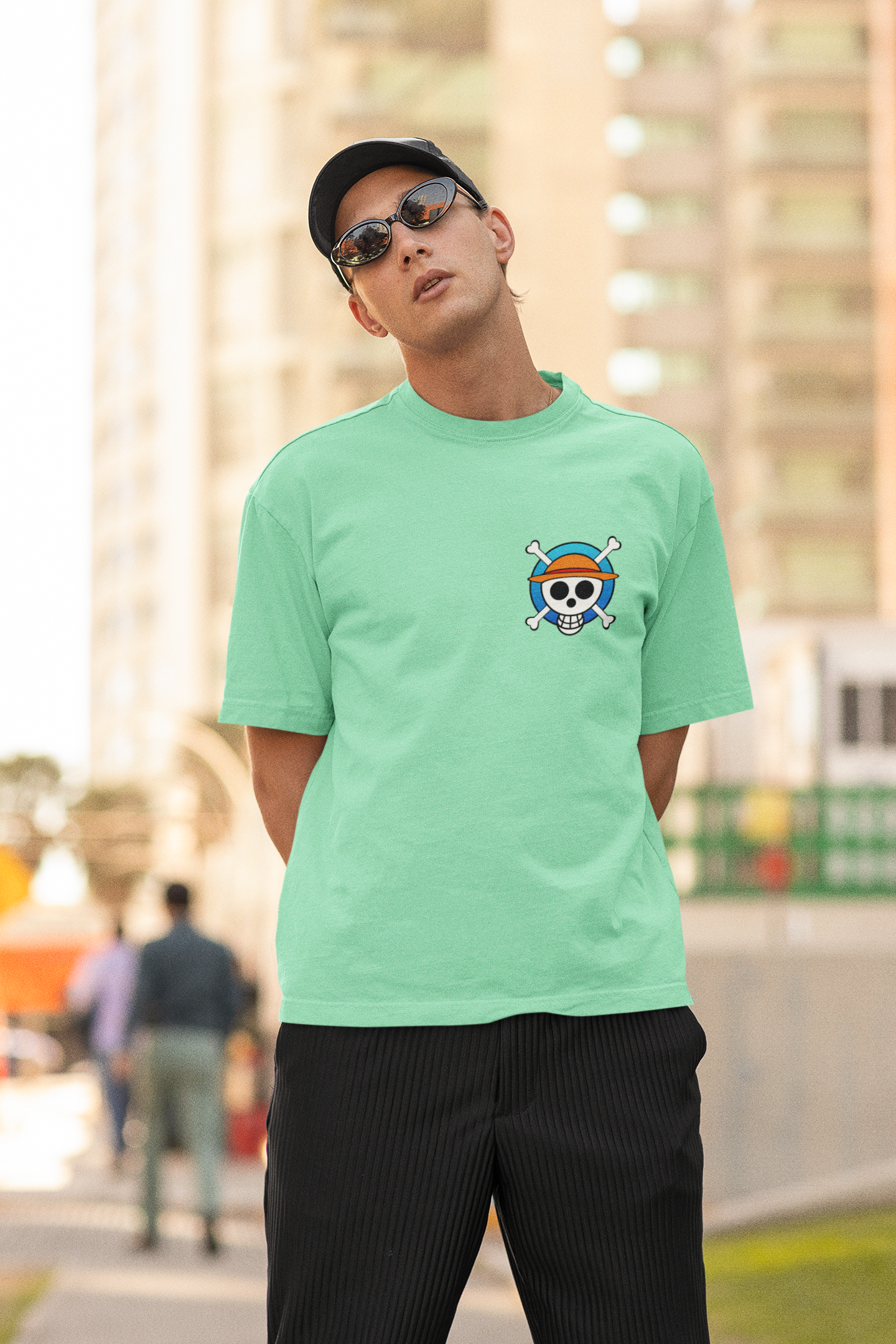 2nd front view of a male model wearing a mint green oversized t-shirt featuring chibi versions of the main characters from the One Piece anime.