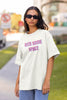 Front view of a female model wearing a white oversized t-shirt with a bold graphic that reads 