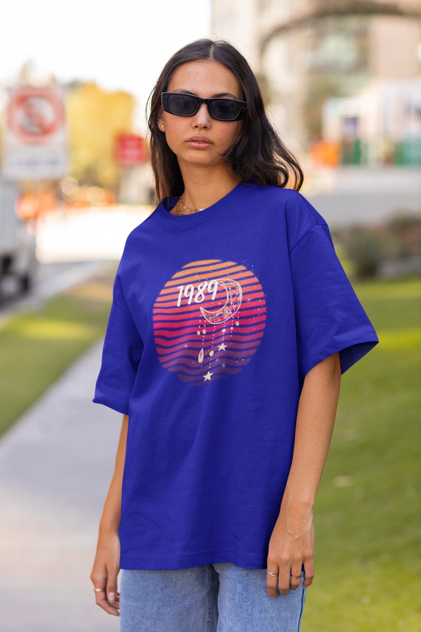 Front view of woman wearing blue coloured Oversize T-shirt featuring Taylor Swift 1989 design, Taylor's Version, and Eras Tour Merch