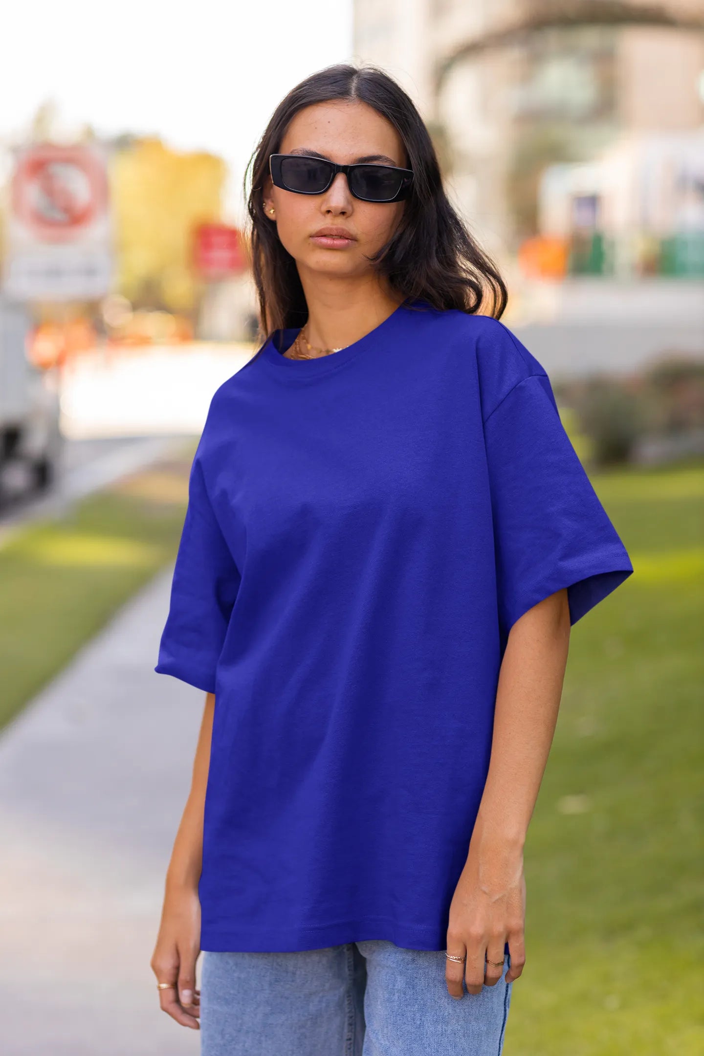 Front view of female model wearing a royal blue oversized t-shirt featuring a captivating "moonlight" design with subtle elements of the Milky Way galaxy, planets, and the soft glow of the moon.