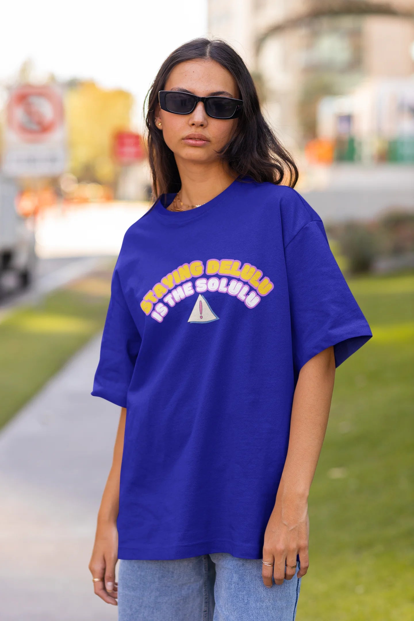 Front view of female model wearing an royal blue oversized t-shirt with the hilarious message "Stay Delulu" in a bold design. Ideal for those who love trendy slang and lighthearted humor.