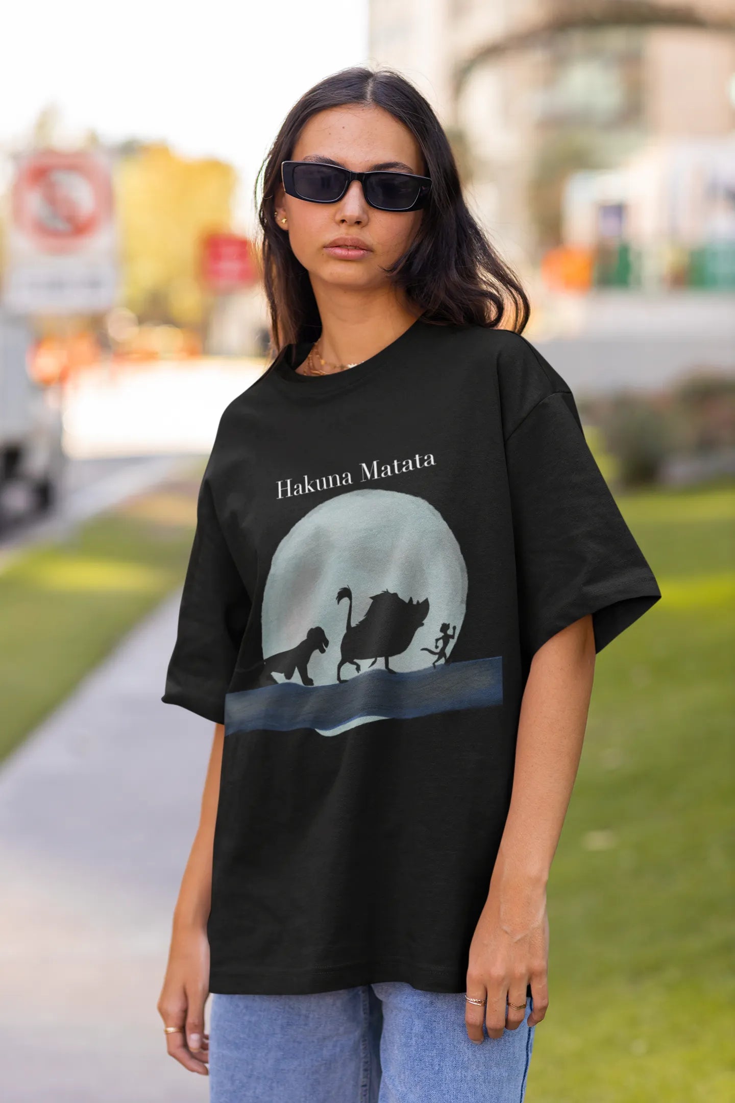 Front view of female model showcasing black oversized t-shirts inspired by Hakuna Matata from Disney's Lion King, featuring Pumbaa, Simba and other iconic characters.