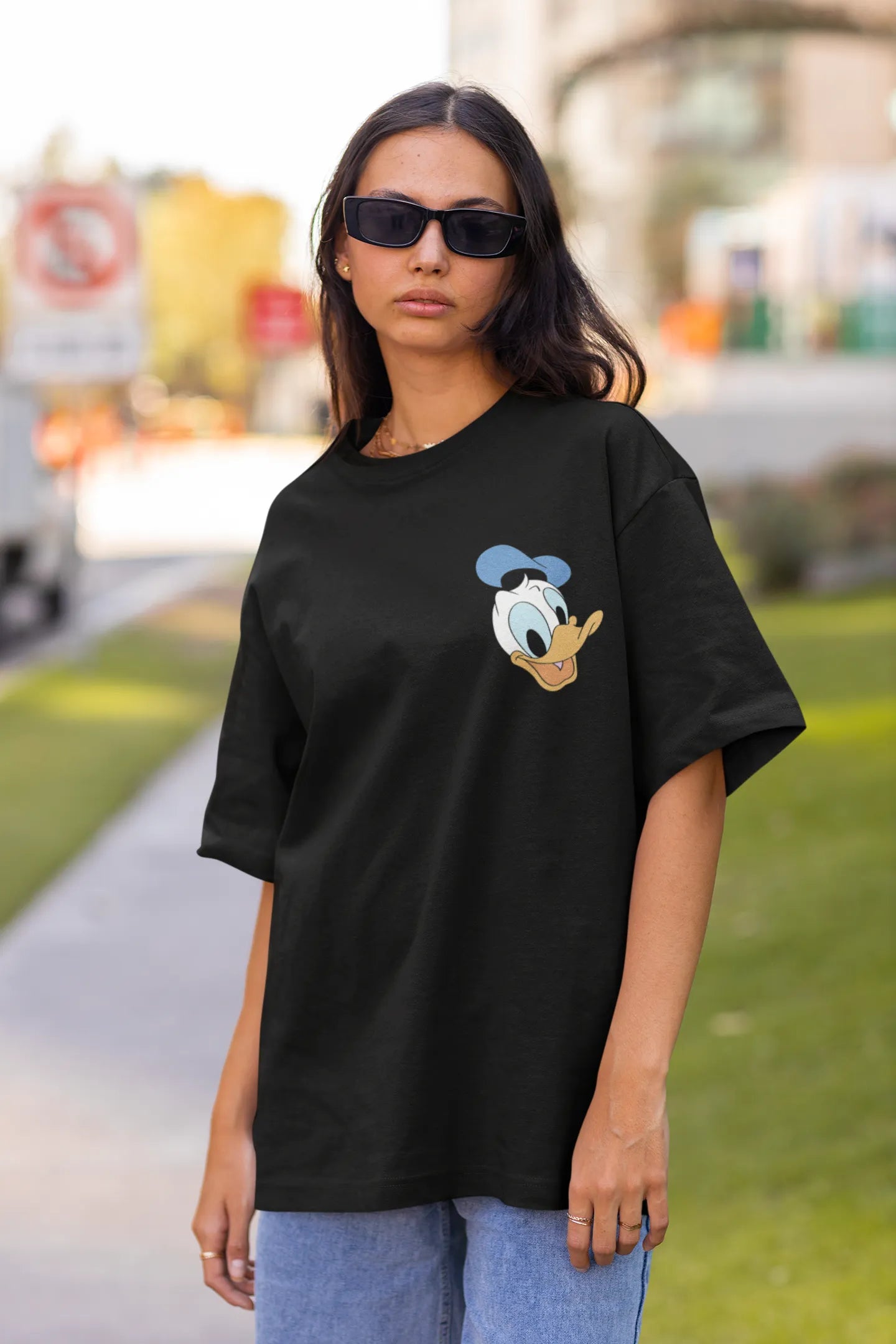 Front view of female model wearing black oversized Disney collection t-shirt featuring a classic Donald Duck design.