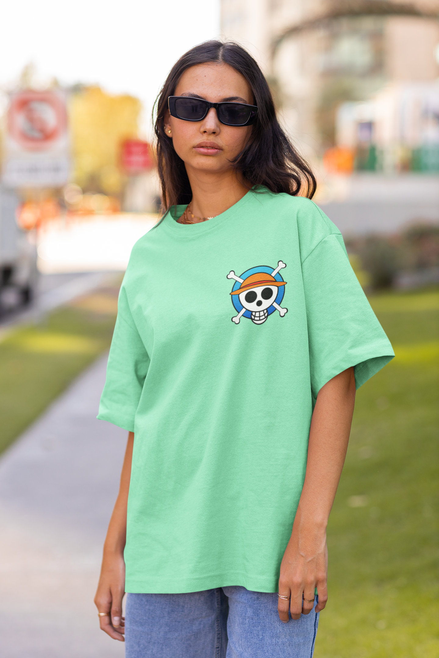 2nd front view of a female model wearing a mint green oversized t-shirt featuring chibi versions of the main characters from the One Piece anime.