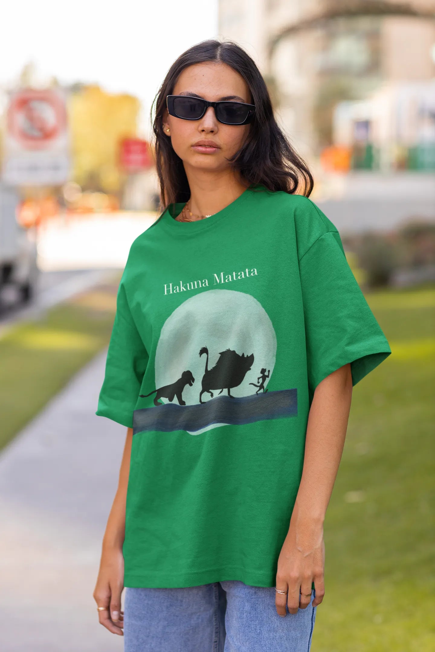 Front view of female model showcasing forest green oversized t-shirts inspired by Hakuna Matata from Disney's Lion King, featuring Pumbaa, Simba and other iconic characters.