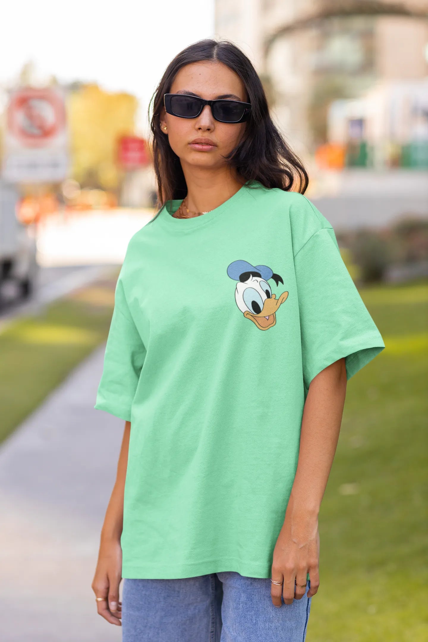 Front view of female model wearing mint green oversized Disney collection t-shirt featuring a classic Donald Duck design.