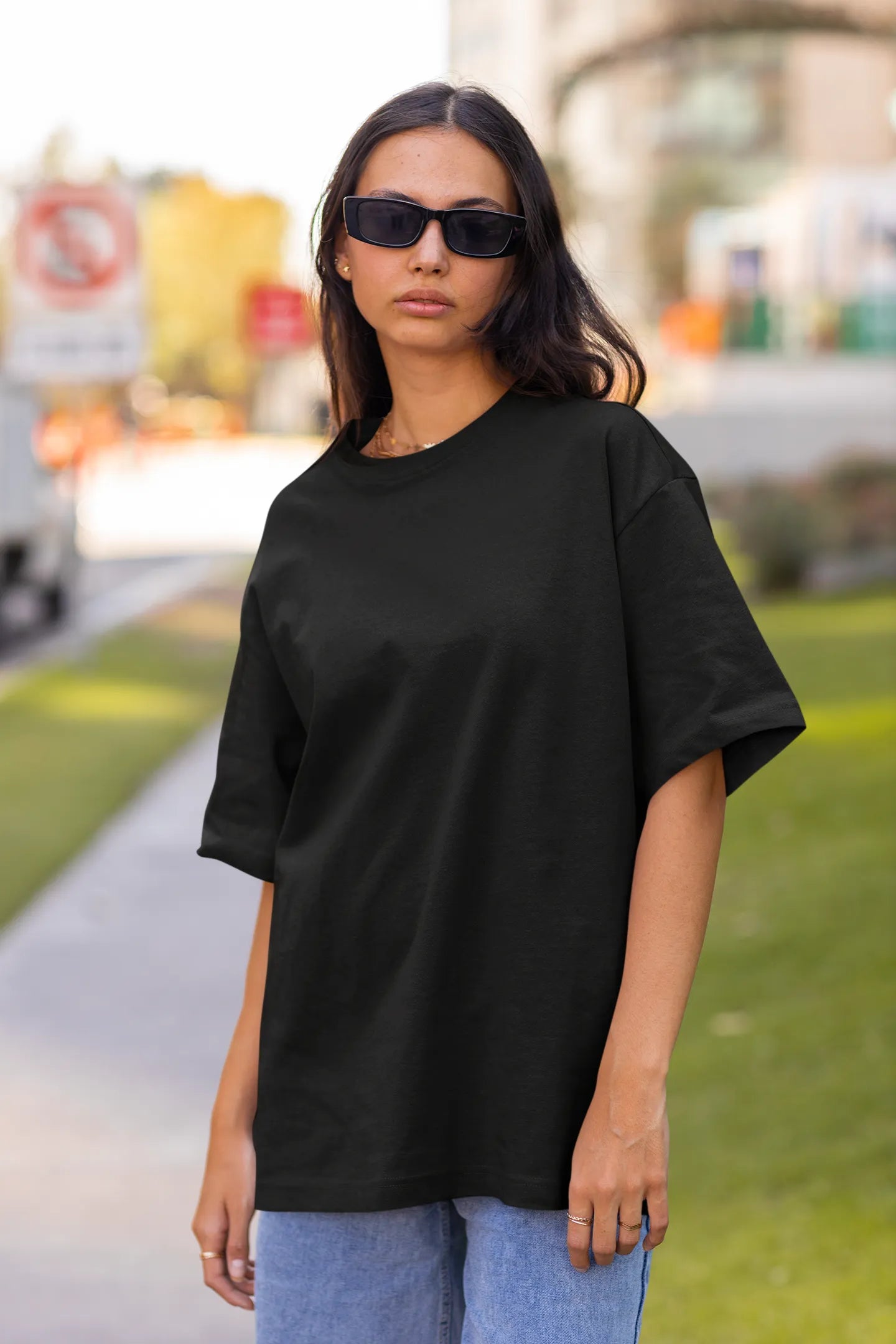 Front view of a female model wearing a black oversized t-shirt featuring a design inspired by the cosmos and galaxies "Fly Me to the Moon" and subtle hints of space exploration.