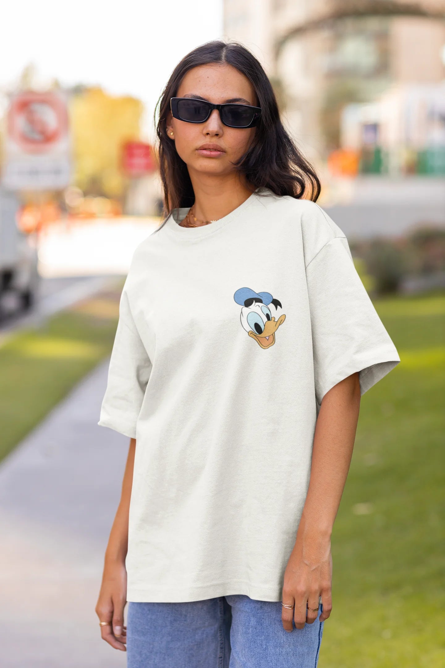 Front view of female model wearing off white oversized Disney collection t-shirt featuring a classic Donald Duck design.