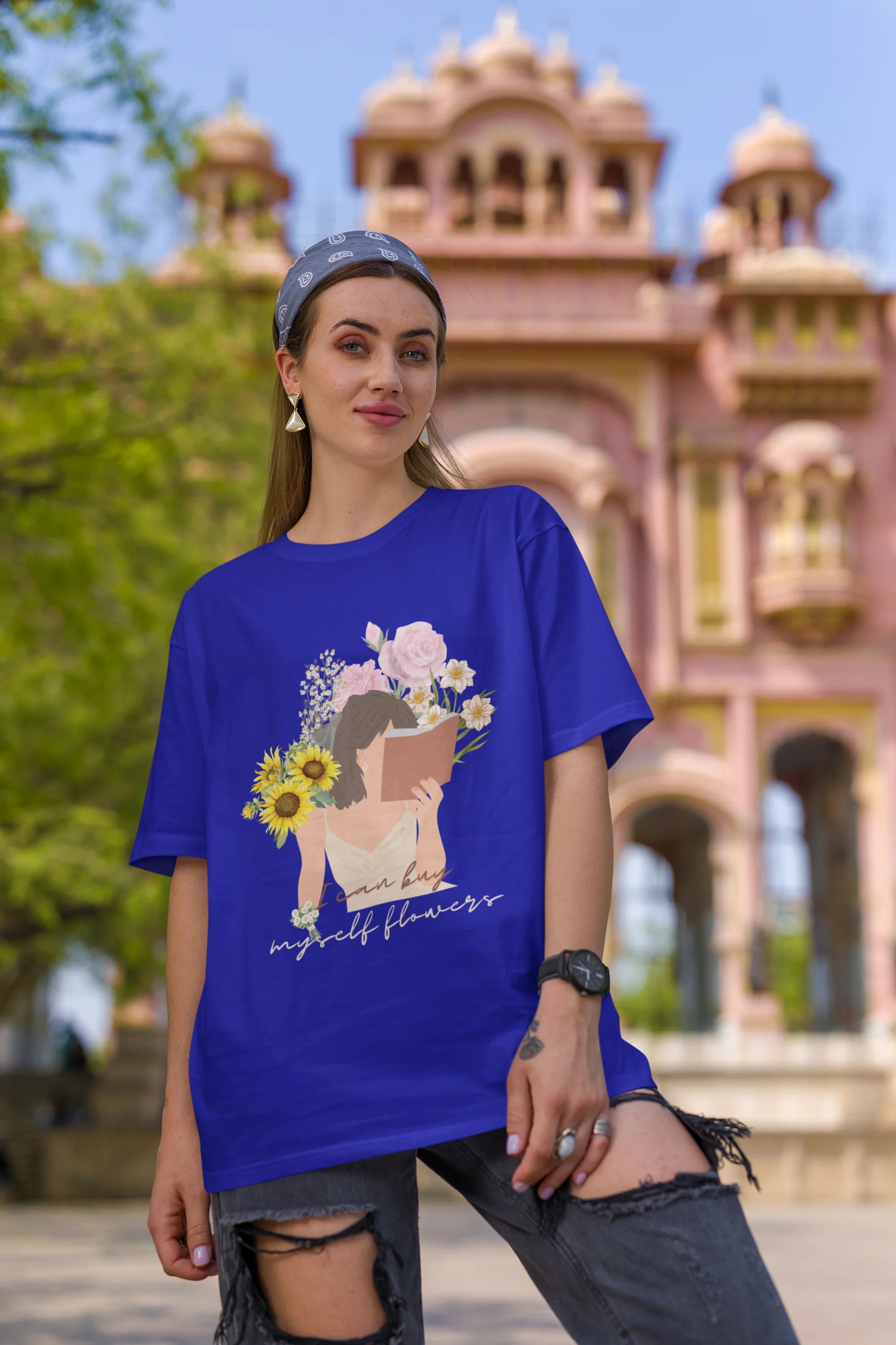 First front view of female model wearing a royal blue oversized t-shirt with a positive message "Buy Myself Flowers" and a graphic of a smiling woman surrounded by tulips and sunflowers. Ideal for those who love inspirational clothing and floral designs.