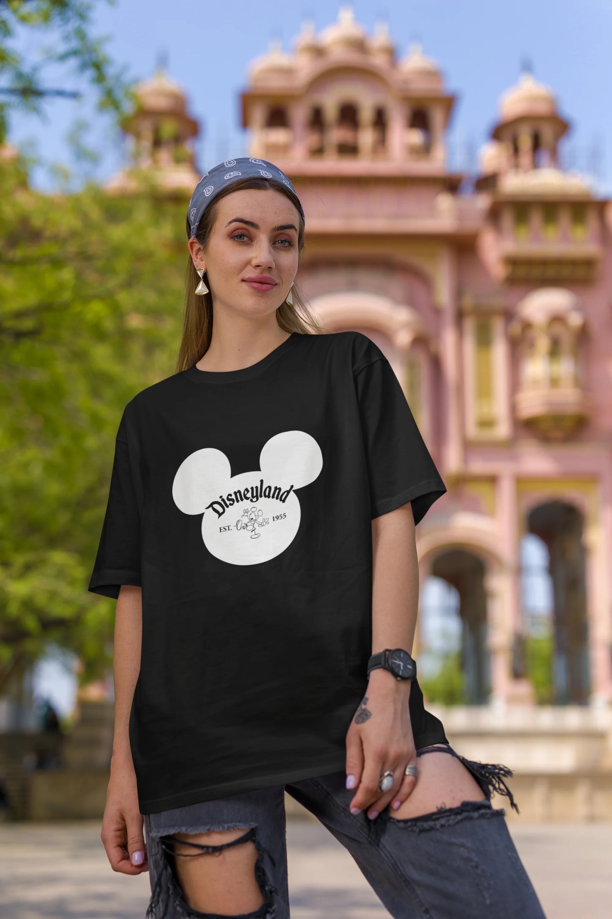 First image of female model wearing an black oversized Disney collection t-shirt featuring a classic Disneyland design.