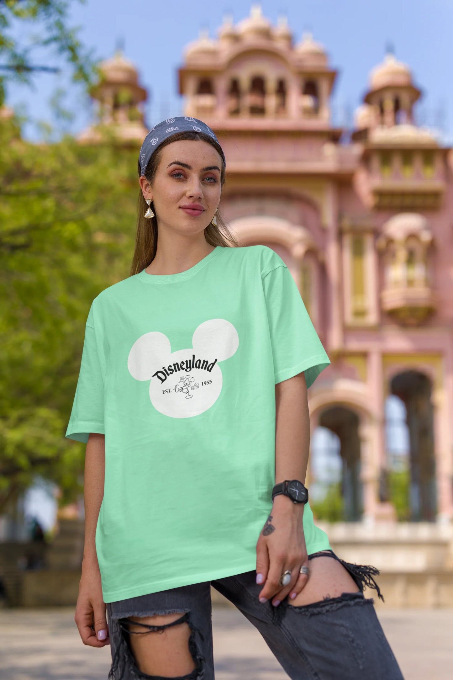 First image of female model wearing a mint green oversized Disney collection t-shirt featuring a classic Disneyland design.