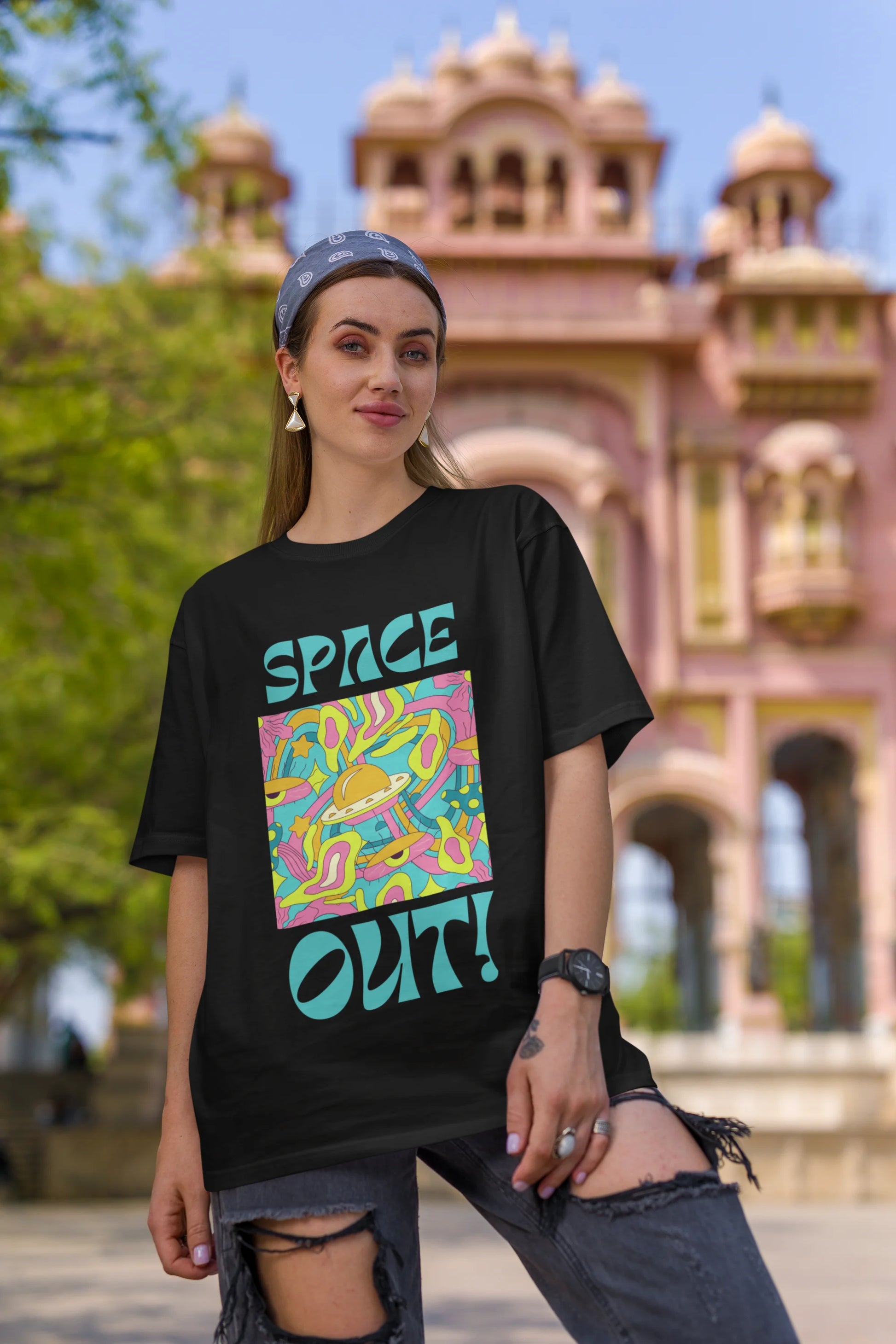 First image of female model wearing an black oversized "Spaced Out" t-shirt featuring a vibrant color mashup design that evokes a sense of space exploration, playful aliens, and distant galaxies.