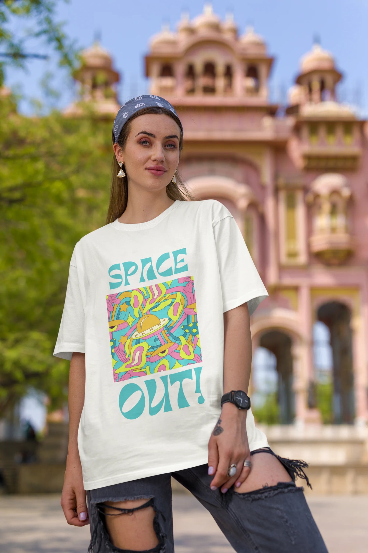 First image of female model wearing an off white oversized "Spaced Out" t-shirt featuring a vibrant color mashup design that evokes a sense of space exploration, playful aliens, and distant galaxies.