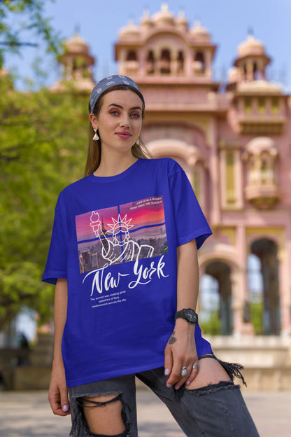 First front view of a female model wearing a royal blue oversized t-shirt with a New York City skyline design, offering a relaxed urban aesthetic.