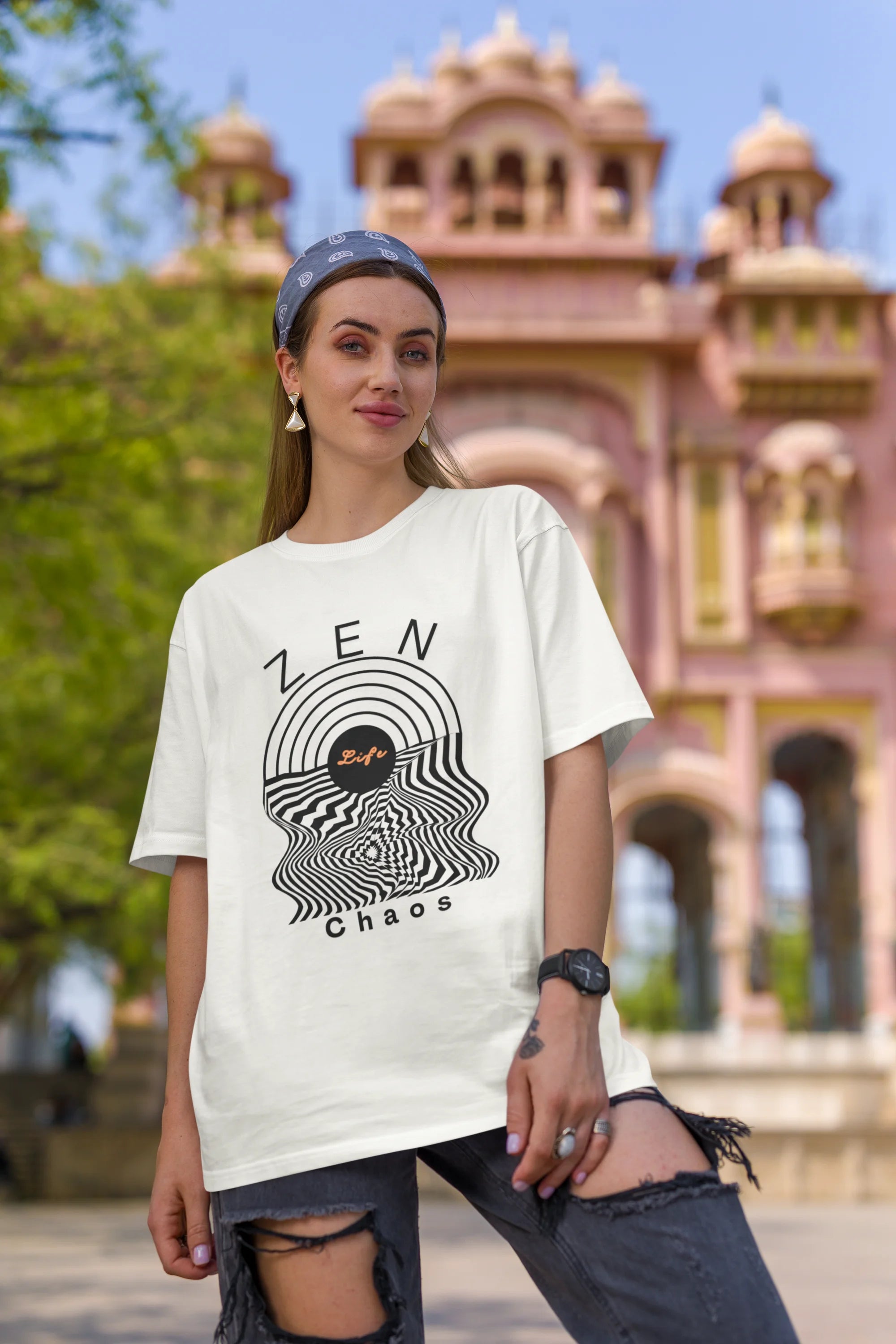 First front image of a female model wearing an off-white oversized t-shirt featuring an aesthetic design of a setting sun and crashing waves with the text "Zen & Chaos" above it. Ideal for those who love philosophical themes and visually striking clothing.