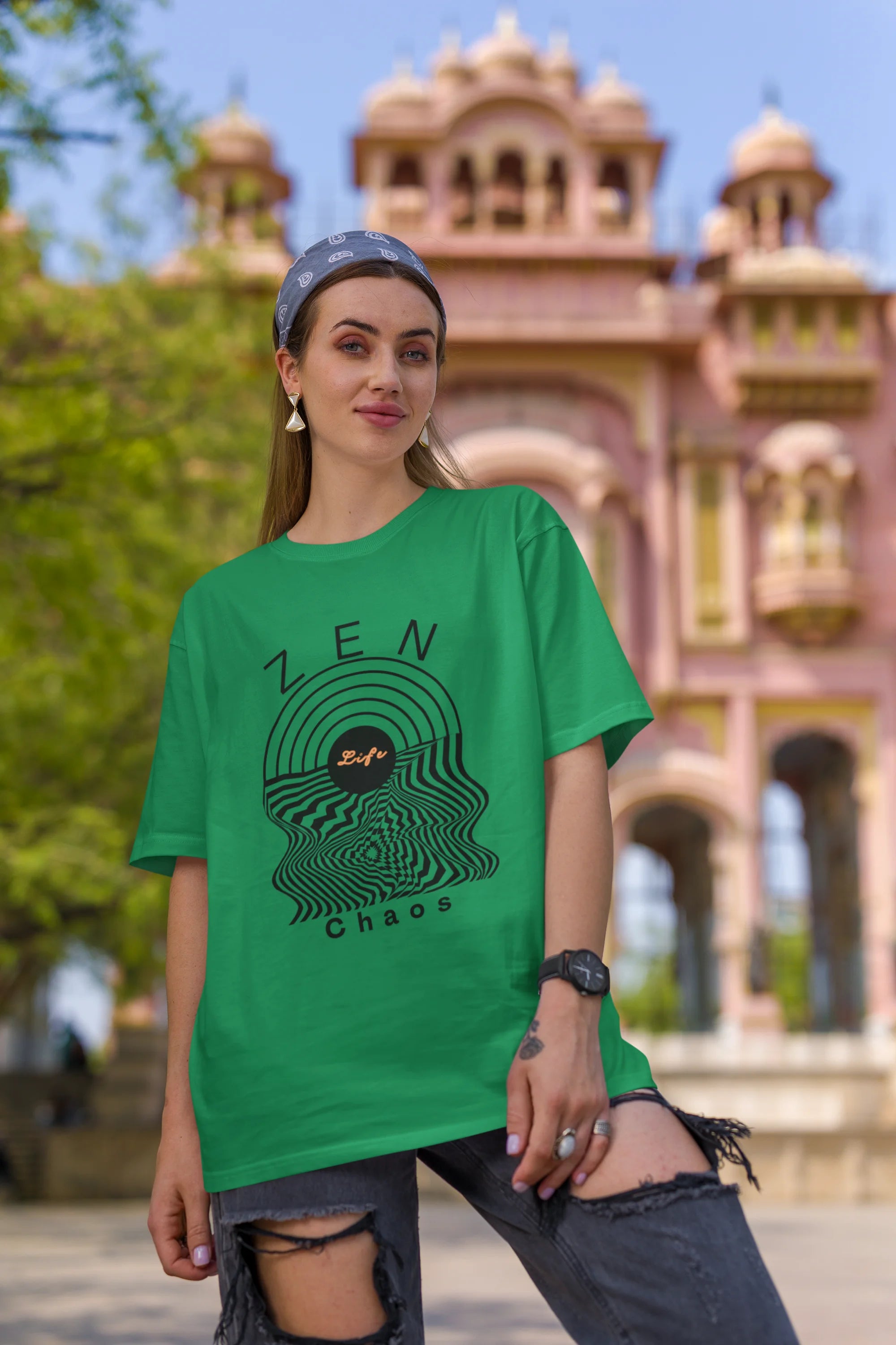 First front view of a female model wearing an forest green oversized t-shirt featuring an aesthetic design of a setting sun and crashing waves with the text "Zen & Chaos" above it. Ideal for those who love philosophical themes and visually striking clothing.