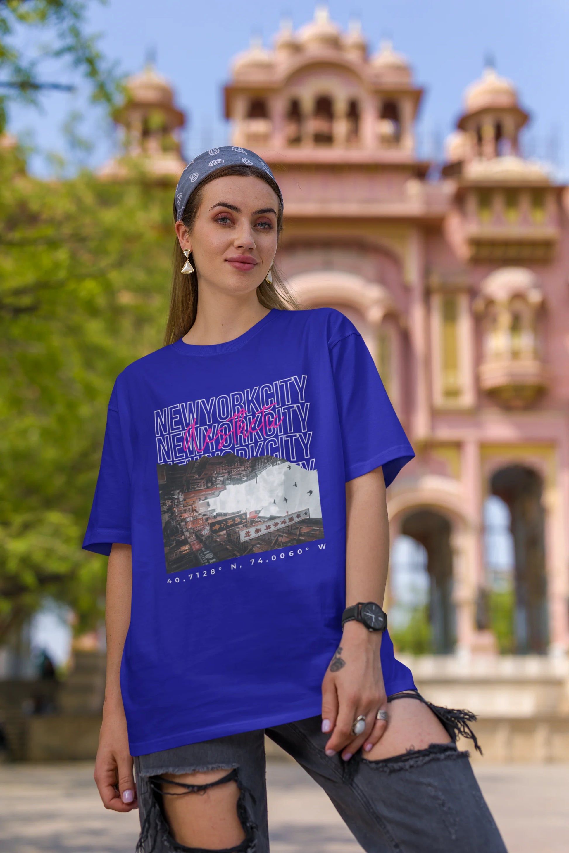 First front view of a female model wearing a royal blue oversized t-shirt with a New York City skyline design, offering a relaxed urban aesthetic.