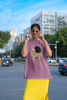 Third front view of female model wearing a dirty purple oversized t-shirt with a design of Shinchan laughing hysterically. Perfect for Shinchan fans who love the character's humor.