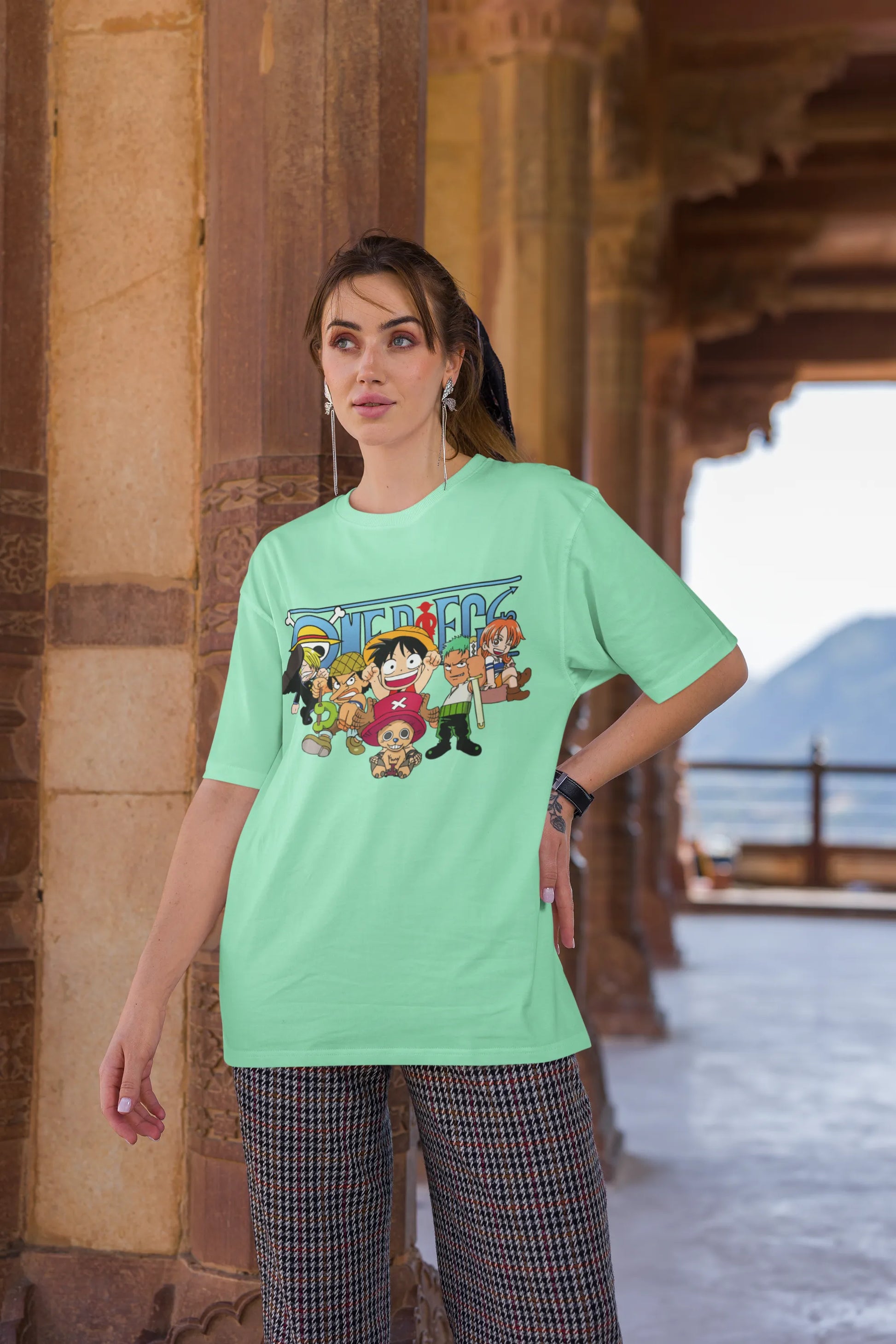 3rd front view of a female model wearing an mint green oversized t-shirt featuring chibi versions of the Straw Hat Crew from the One Piece anime.