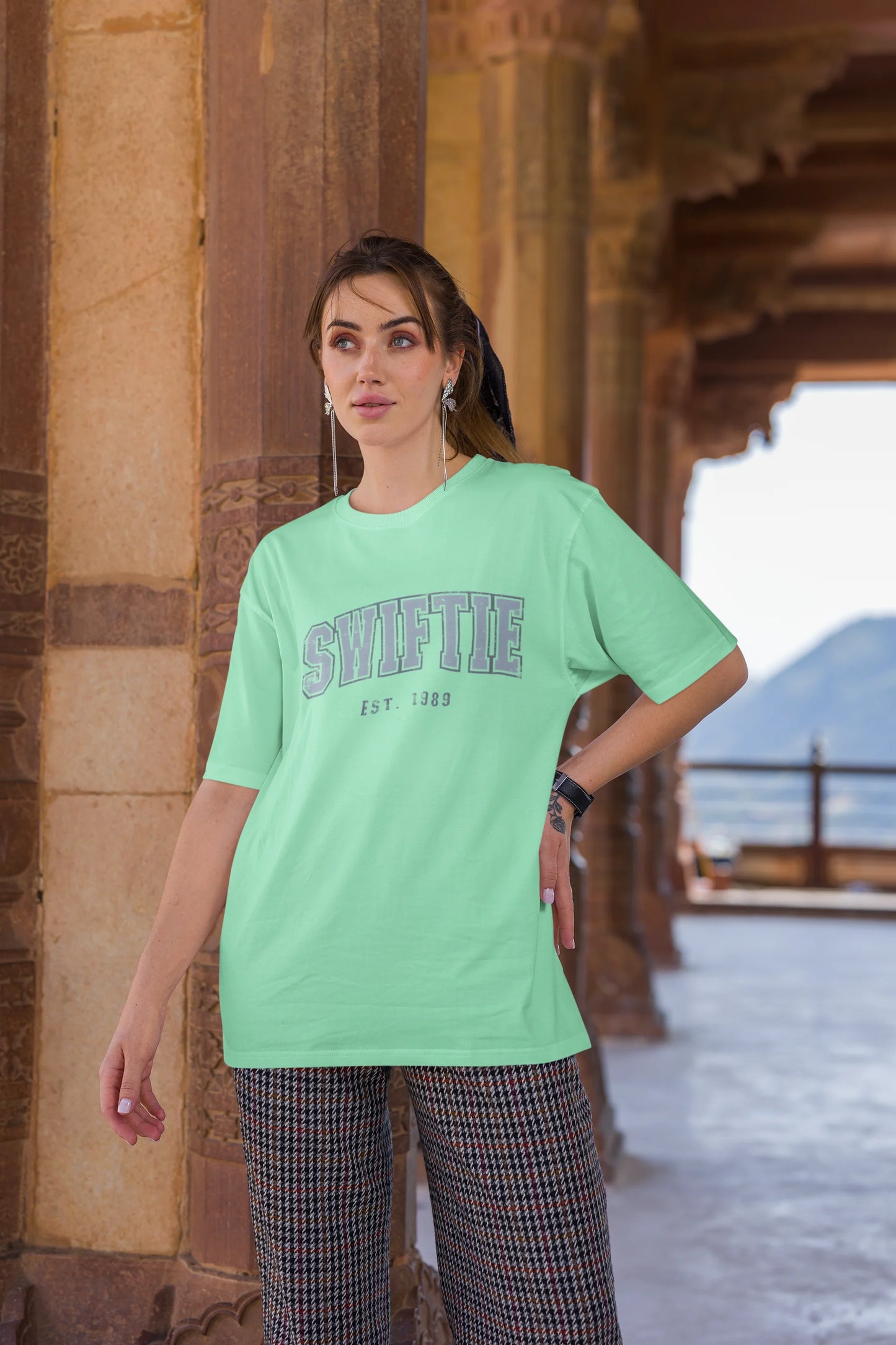 Third image of woman wearing mint green Oversize T-shirt featuring Swiftie design, taylor's version