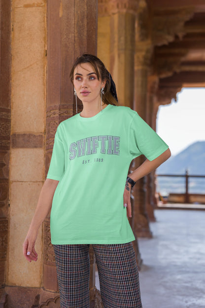 Third image of woman wearing mint green Oversize T-shirt featuring Swiftie design, taylor's version