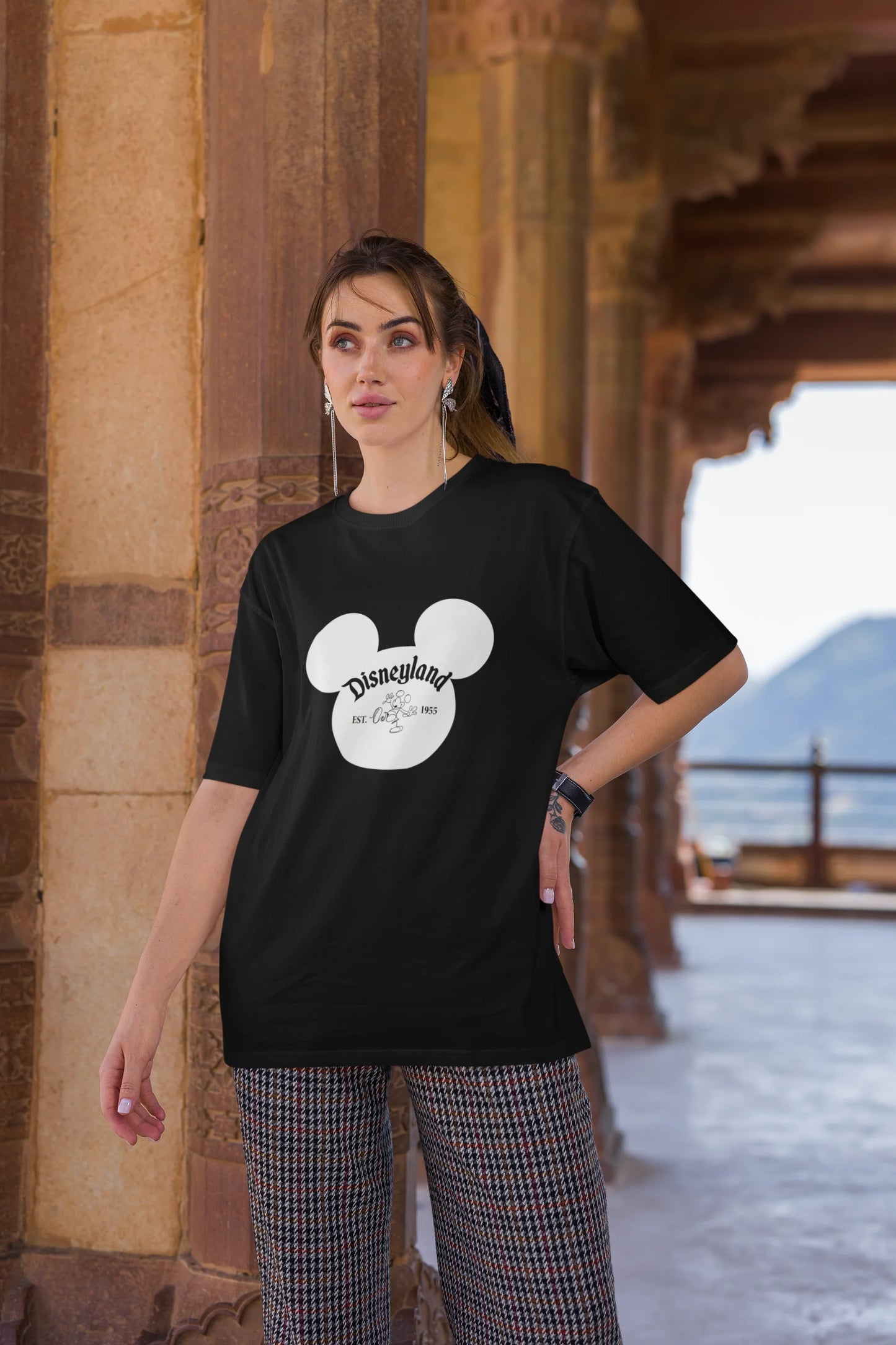 Third image of female model wearing a black oversized Disney collection t-shirt featuring a classic Disneyland design.