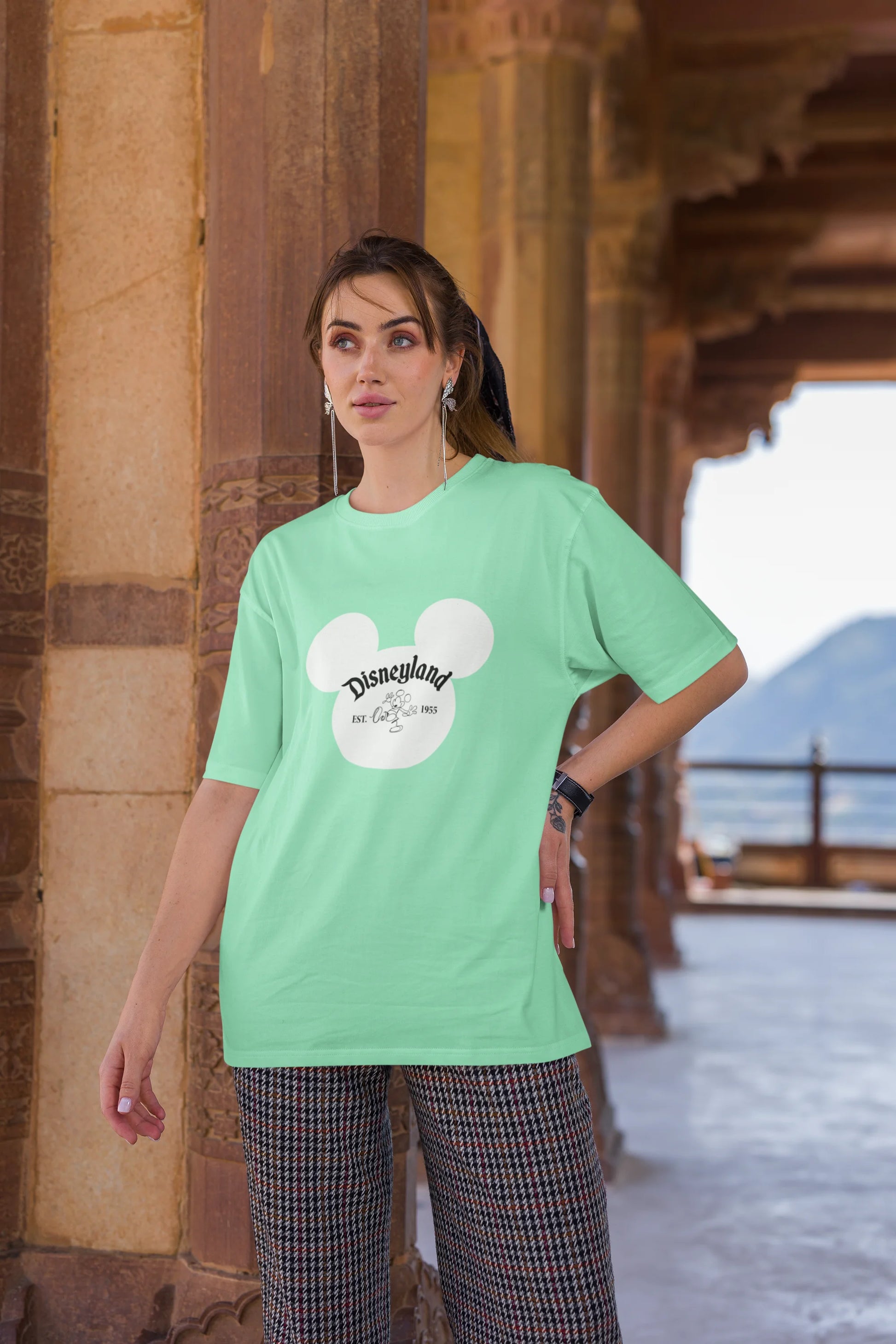 Third image of female model wearing a mint green oversized Disney collection t-shirt featuring a classic Disneyland design.
