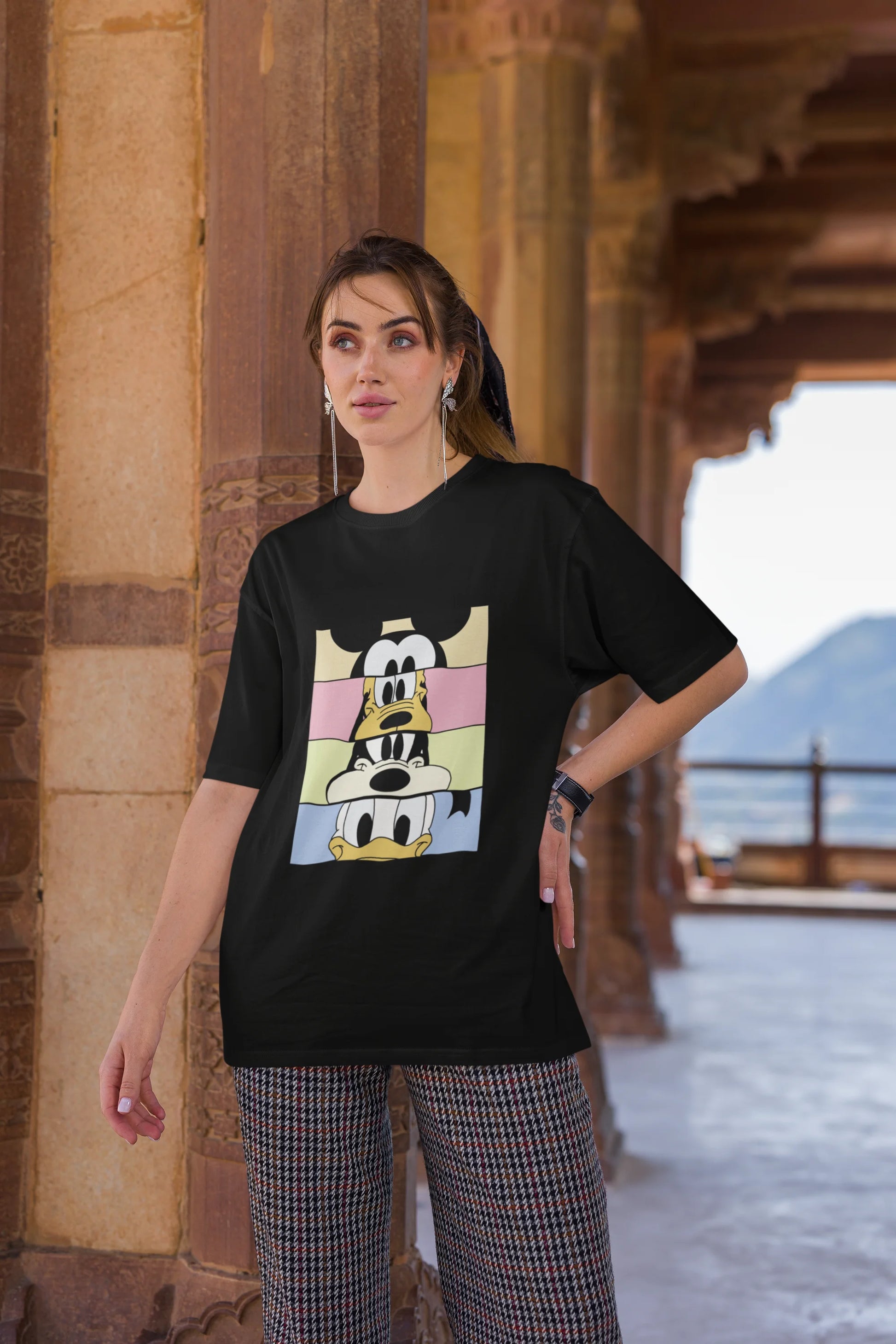 Third image of female Model showcasing black oversized t-shirt inspired by Mickey Mouse Clubhouse characters: Mickey Mouse, Donald Duck, Goofy, and Minnie Mouse