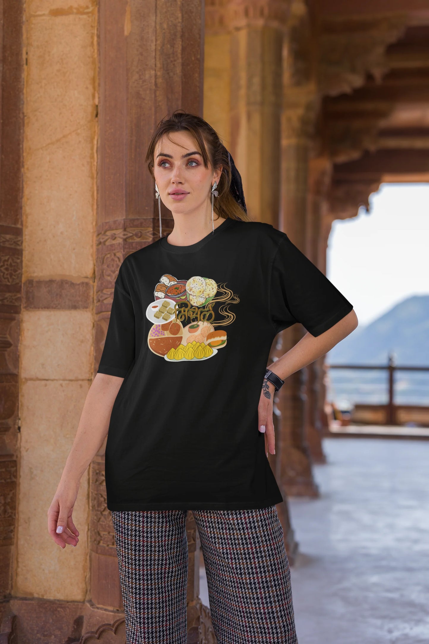 Third front view of female model wearing an black oversized t-shirt featuring a design inspired by the Marathi dish Misal Pav. Ideal for fans of Marathi culture, foodies, and anyone who loves a flavorful meal.