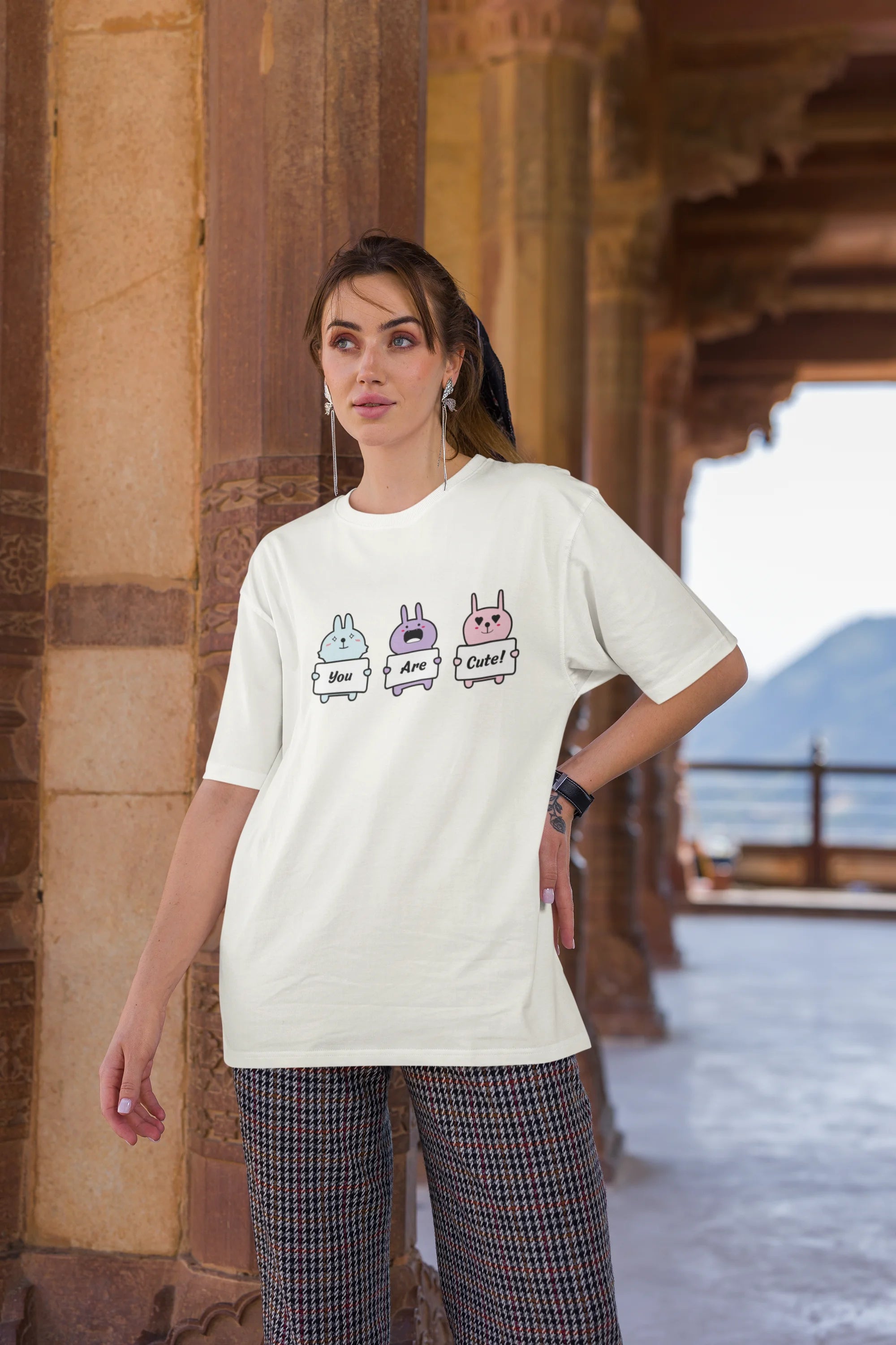 Third image of female model wearing Disney-themed off-white oversized tee with a cute cartoon design