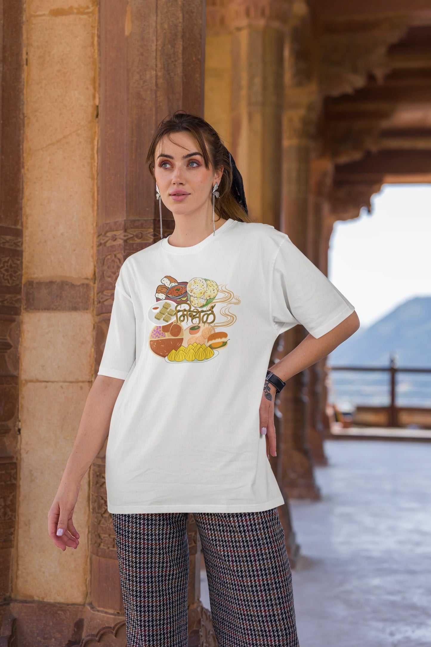 Third front view of female model wearing an off white oversized t-shirt featuring a design inspired by the Marathi dish Misal Pav. Ideal for fans of Marathi culture, foodies, and anyone who loves a flavorful meal.