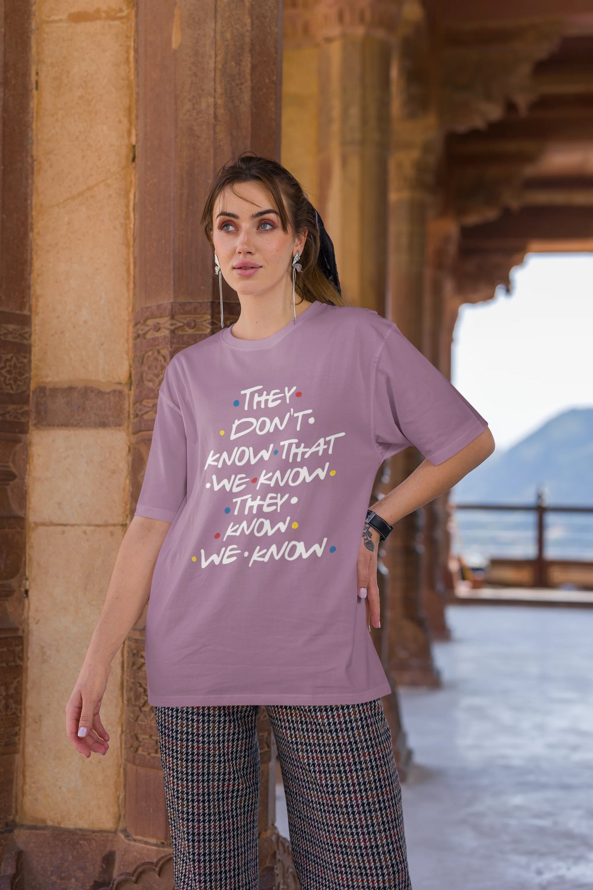 Third image of female model wearing dirty purple oversized t-shirt with F.R.I.E.N.D.S series inspired designs, embodying Phoebe's unique humor with the quote 'They Know We Know'