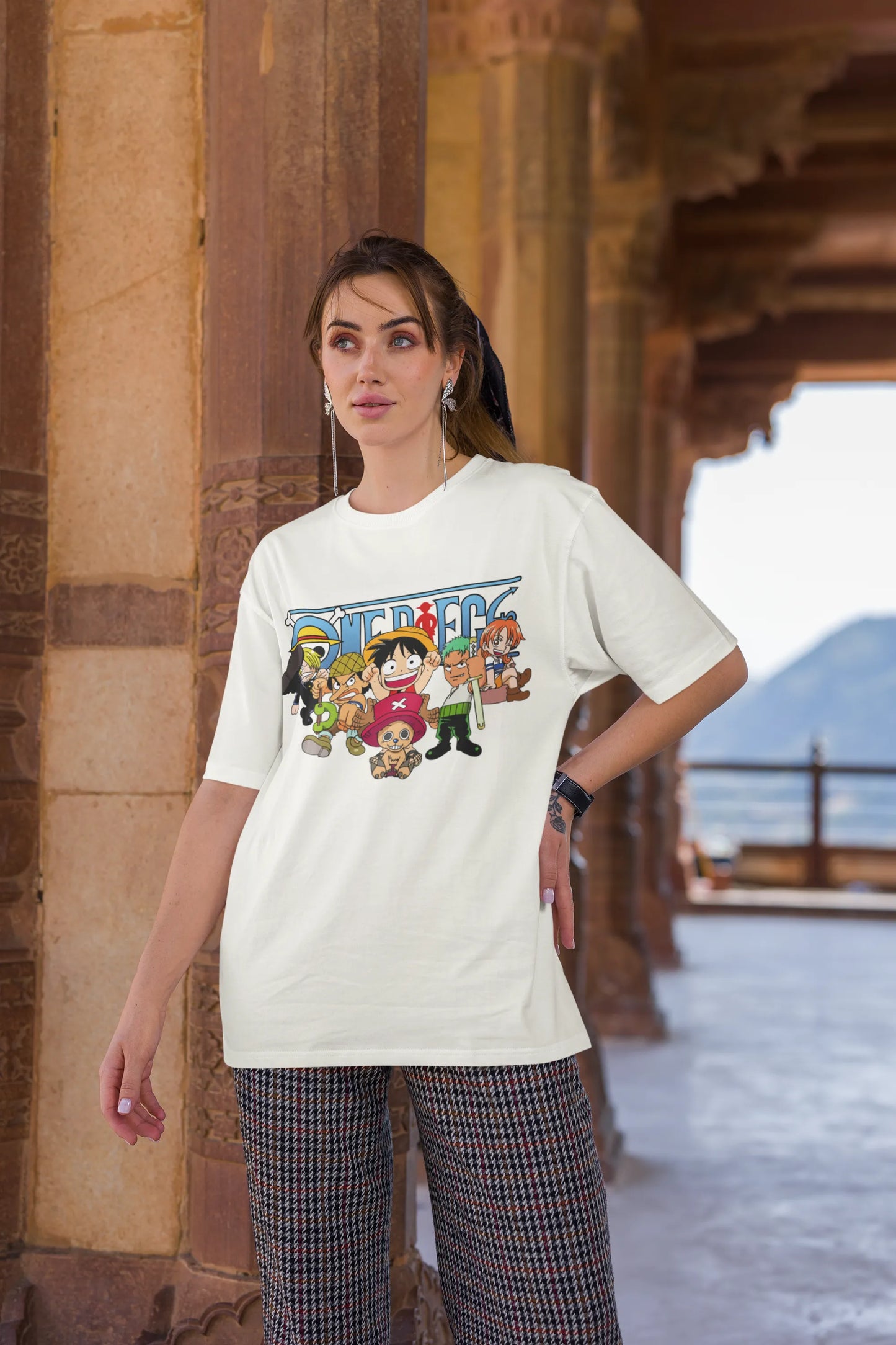 3rd front view of a female model wearing an off-white oversized t-shirt featuring chibi versions of the Straw Hat Crew from the One Piece anime.