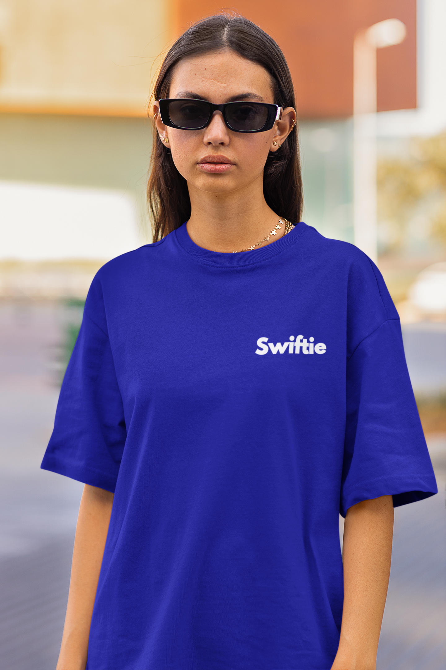 Closeup front view of woman wearing blue coloured Oversize T-shirt featuring Taylor Swift 1989 design, Taylor's Version, and Eras Tour Merch