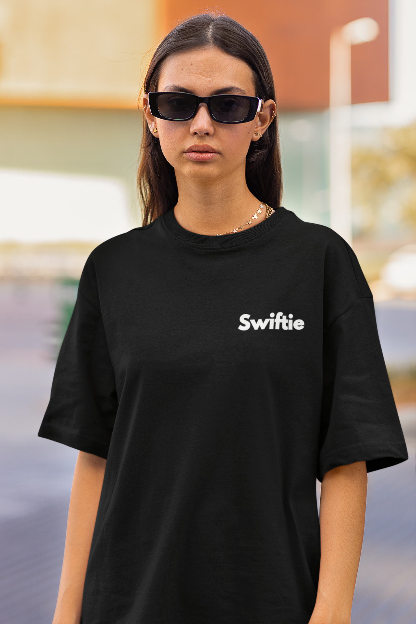 Close up front view of female model flaunting Taylor Swift-themed black oversized tee, epitomizing rockstar chic with nods to Taylor's Version and Eras Tour.