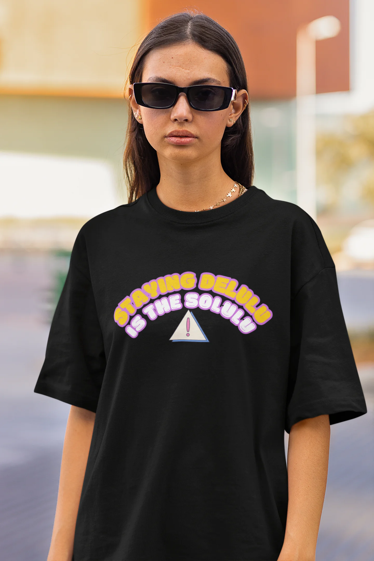 Closeup front view of female model wearing a black oversized t-shirt with the hilarious message "Stay Delulu" in a bold design. Ideal for those who love trendy slang and lighthearted humor.