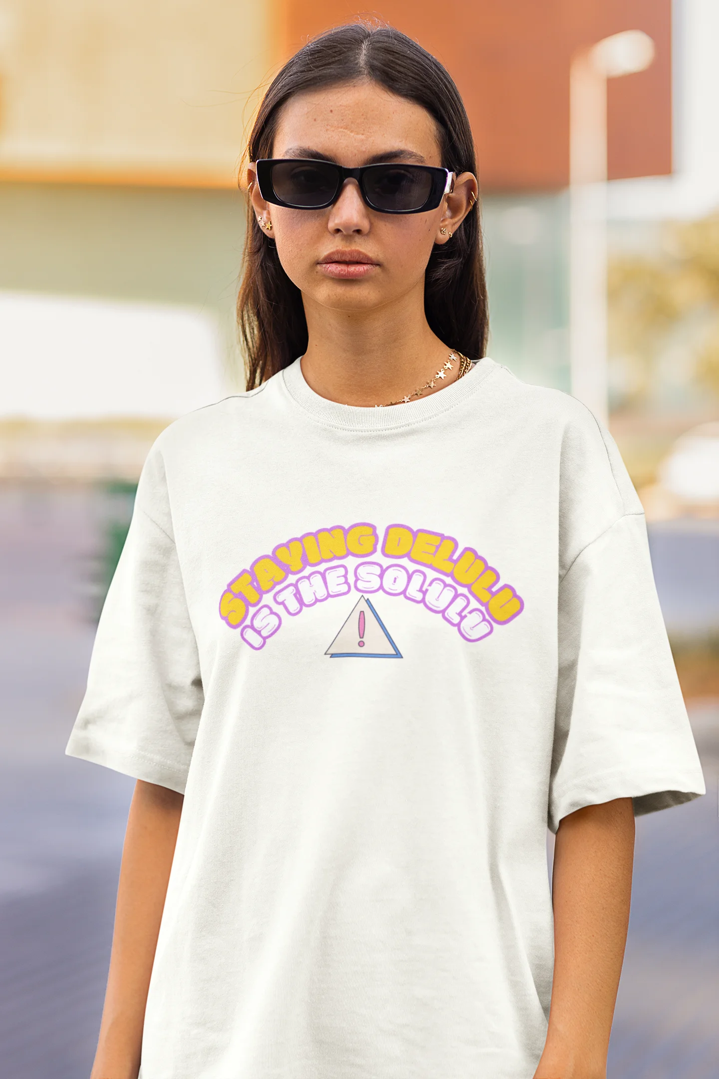 Close up front view of female model wearing an off-white oversized t-shirt with the hilarious message "Stay Delulu" in a bold design. Ideal for those who love trendy slang and lighthearted humor. 