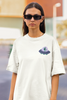 Close up front view of a female model wearing a off-white oversized t-shirt featuring a fun 