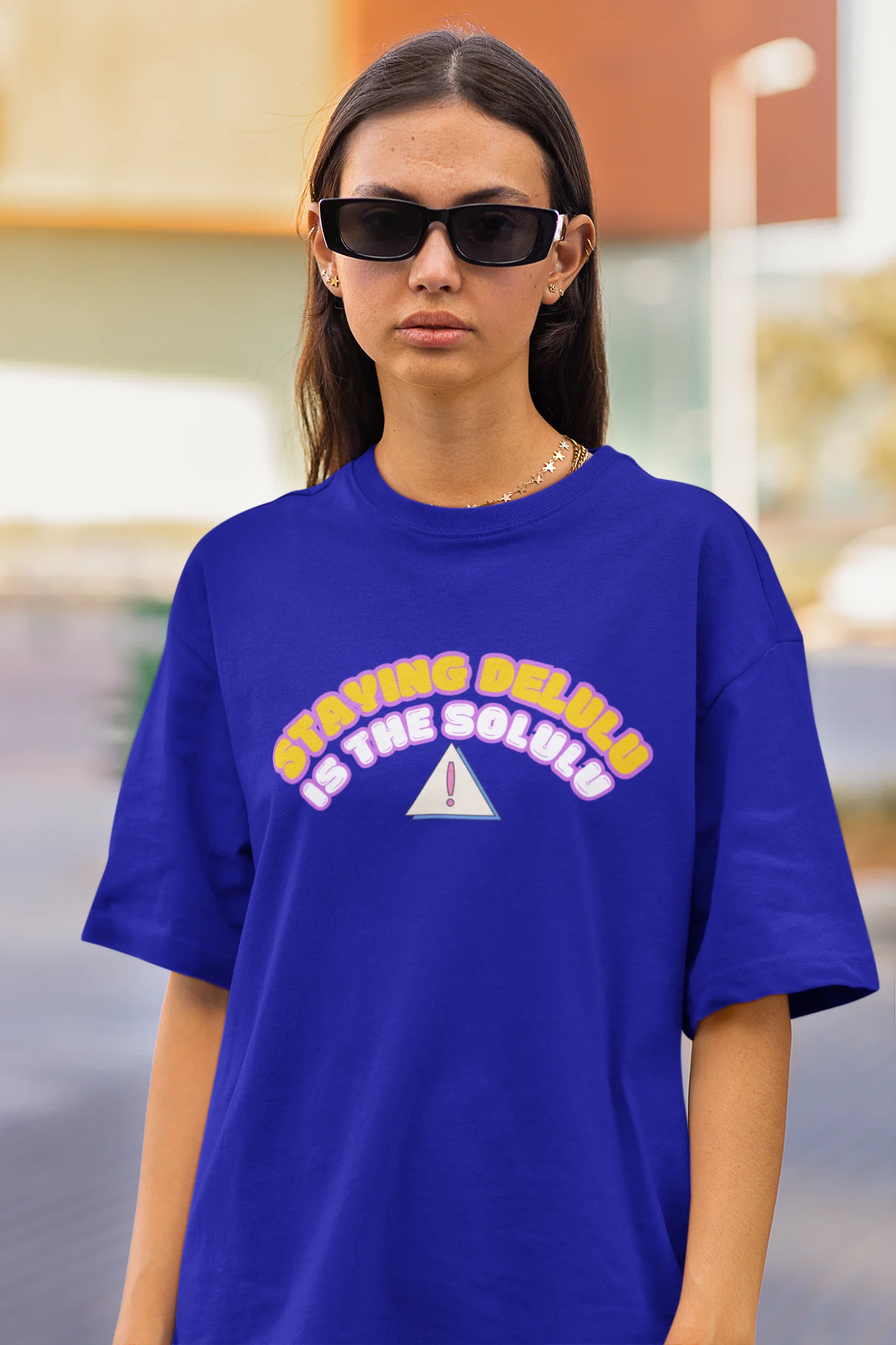 Close up view of female model wearing an royal blue oversized t-shirt with the hilarious message "Stay Delulu" in a bold design. Ideal for those who love trendy slang and lighthearted humor.