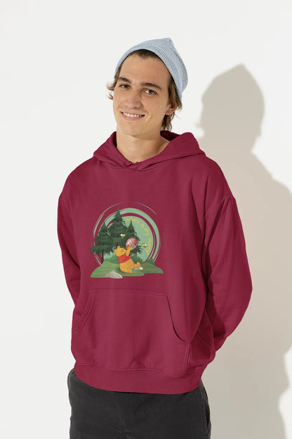 Front view of a male model wearing a maroon hoodie with a Winnie the Pooh design, showing the Disney bear eating honey from a jar in a forest.