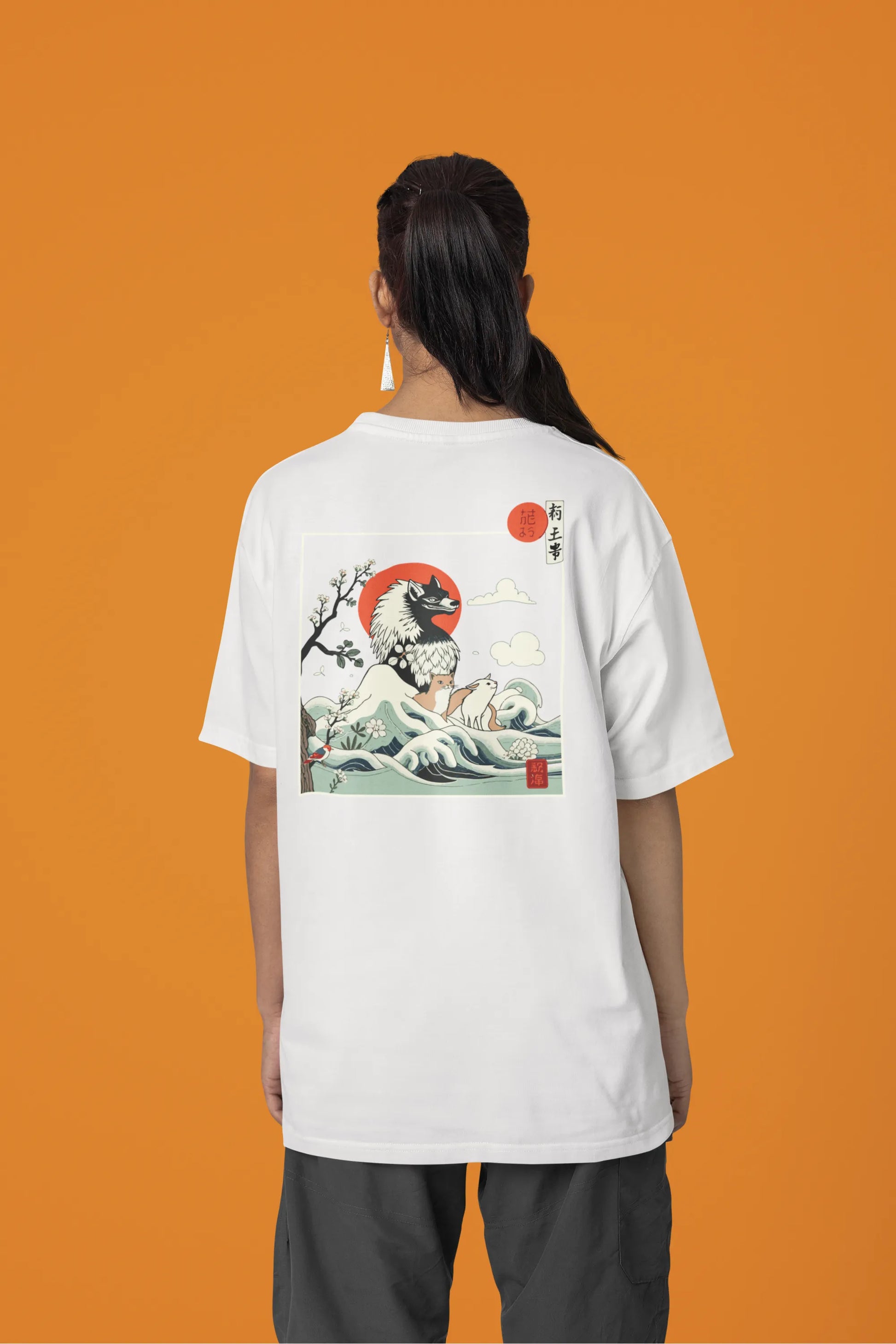 Back view of a female model wearing a off-white oversized tee with a design of a wolf surveying a Japanese landscape.