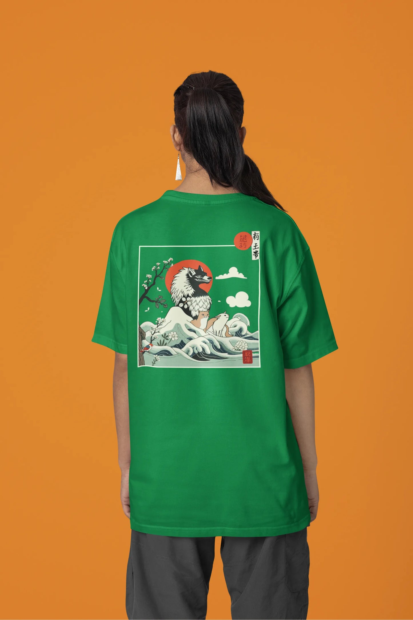 Back view of a female model wearing a forest green oversized tee with a design of a wolf surveying a Japanese landscape.