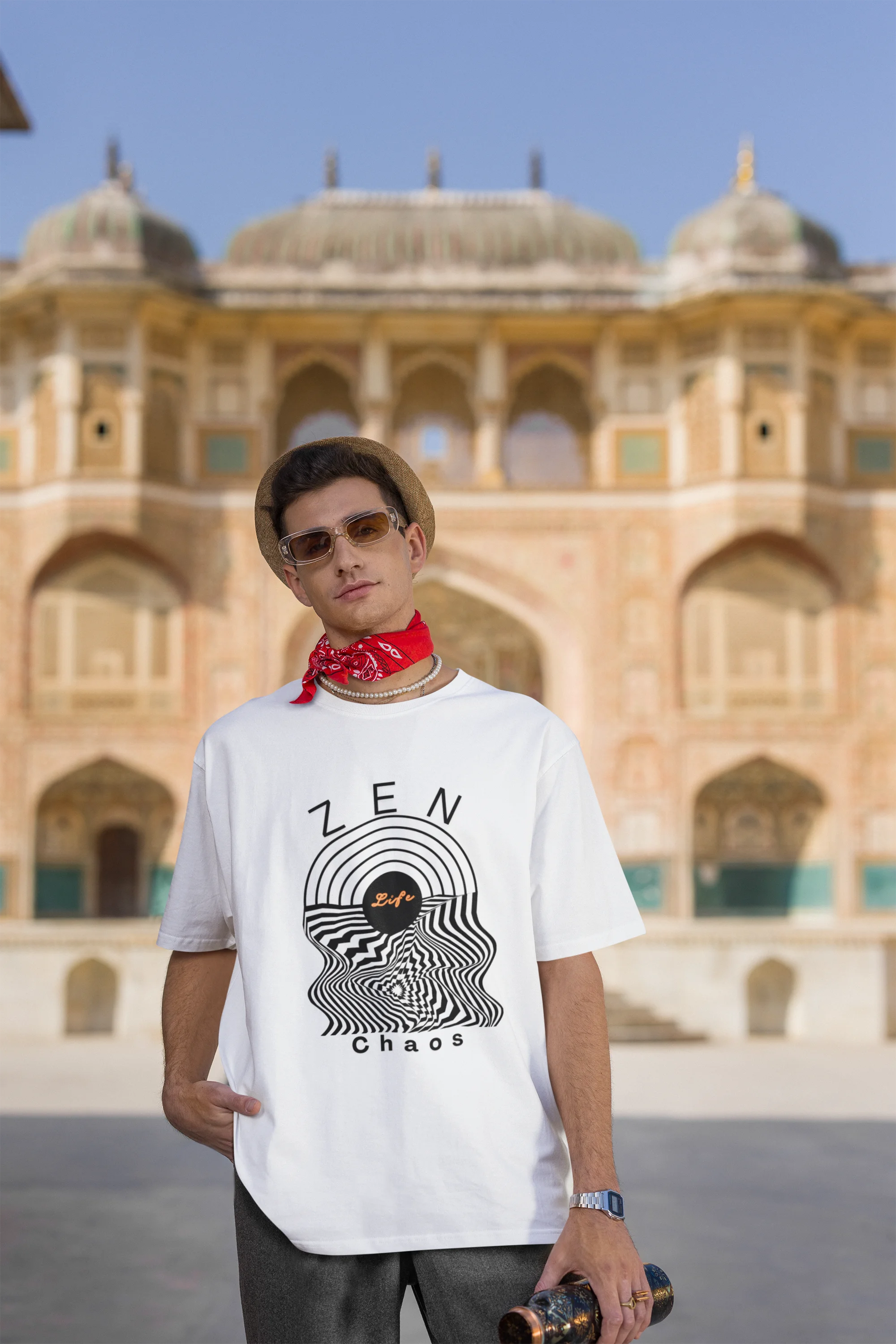 Third front image of a male model wearing an off-white oversized t-shirt featuring an aesthetic design of a setting sun and crashing waves with the text "Zen & Chaos" above it. Ideal for those who love philosophical themes and visually striking clothing.