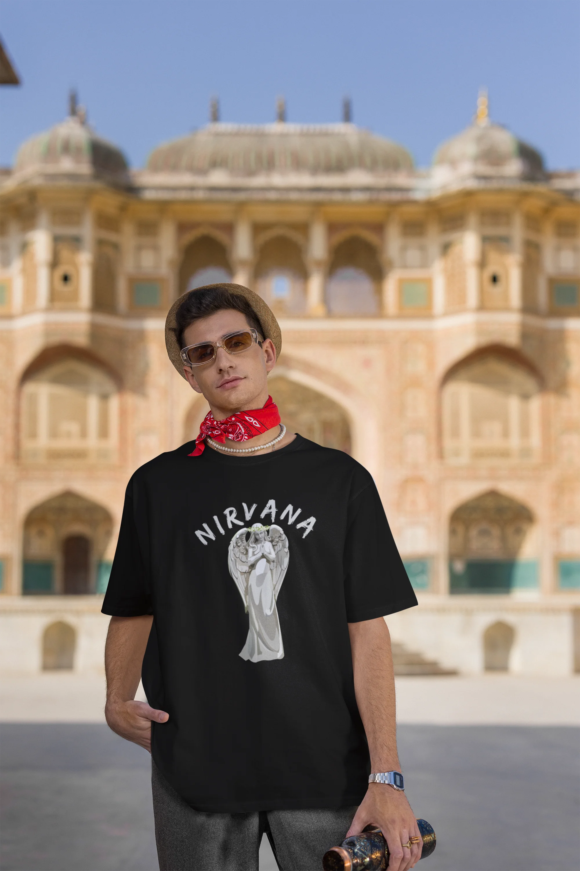 Third front image of male model wearing a black oversized t-shirt featuring a design of a winged angel with the text "Nirvana" above it. Ideal for fans of Nirvana and those who love grunge aesthetics.