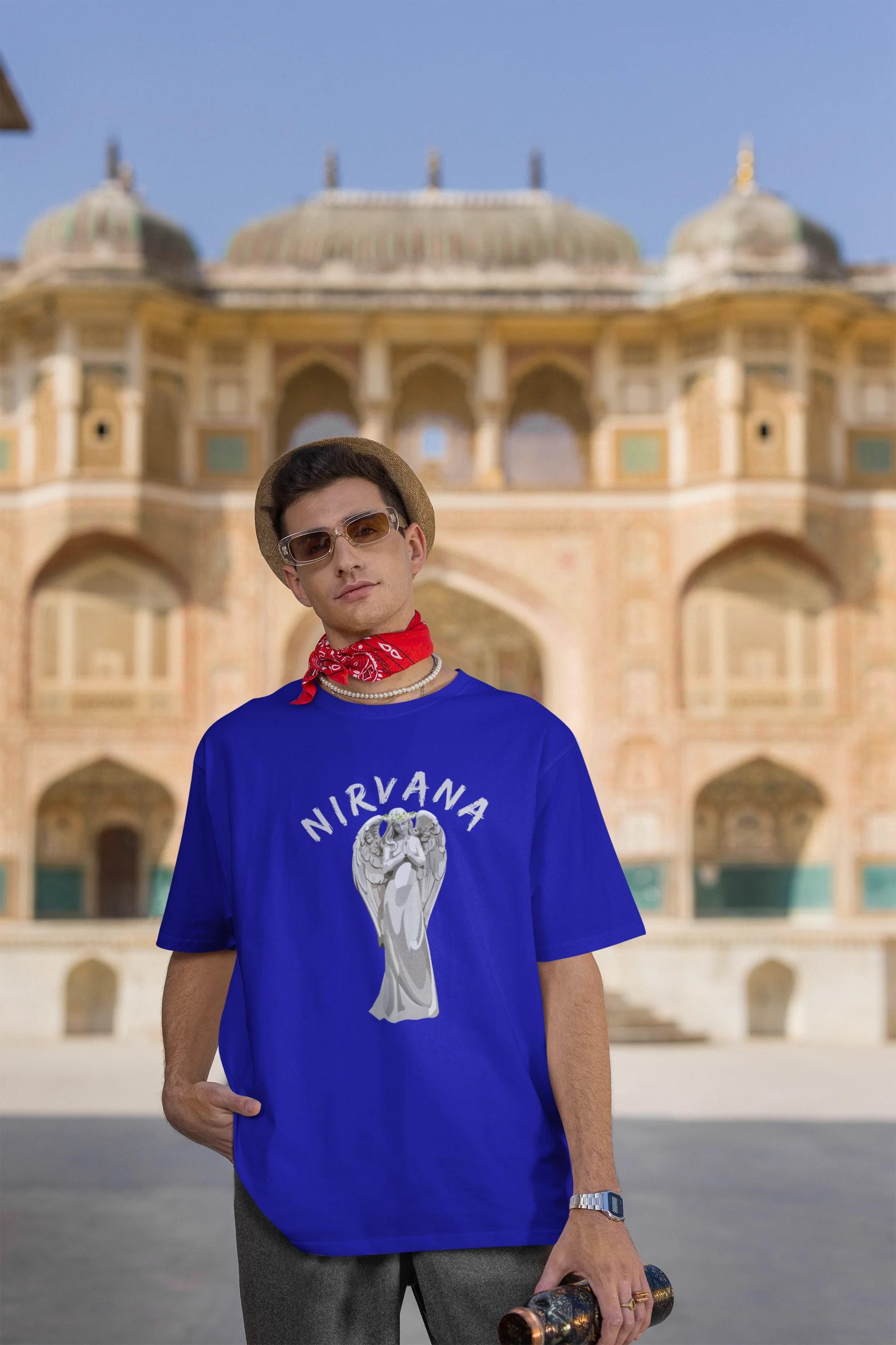 third front image of male model wearing a\ royal blue oversized t-shirt featuring a design of a winged angel with the text "Nirvana" above it. Ideal for fans of Nirvana and those who love grunge aesthetics.