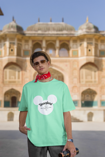 Third image of male model wearing a mint green oversized Disney collection t-shirt featuring a classic Disneyland design.