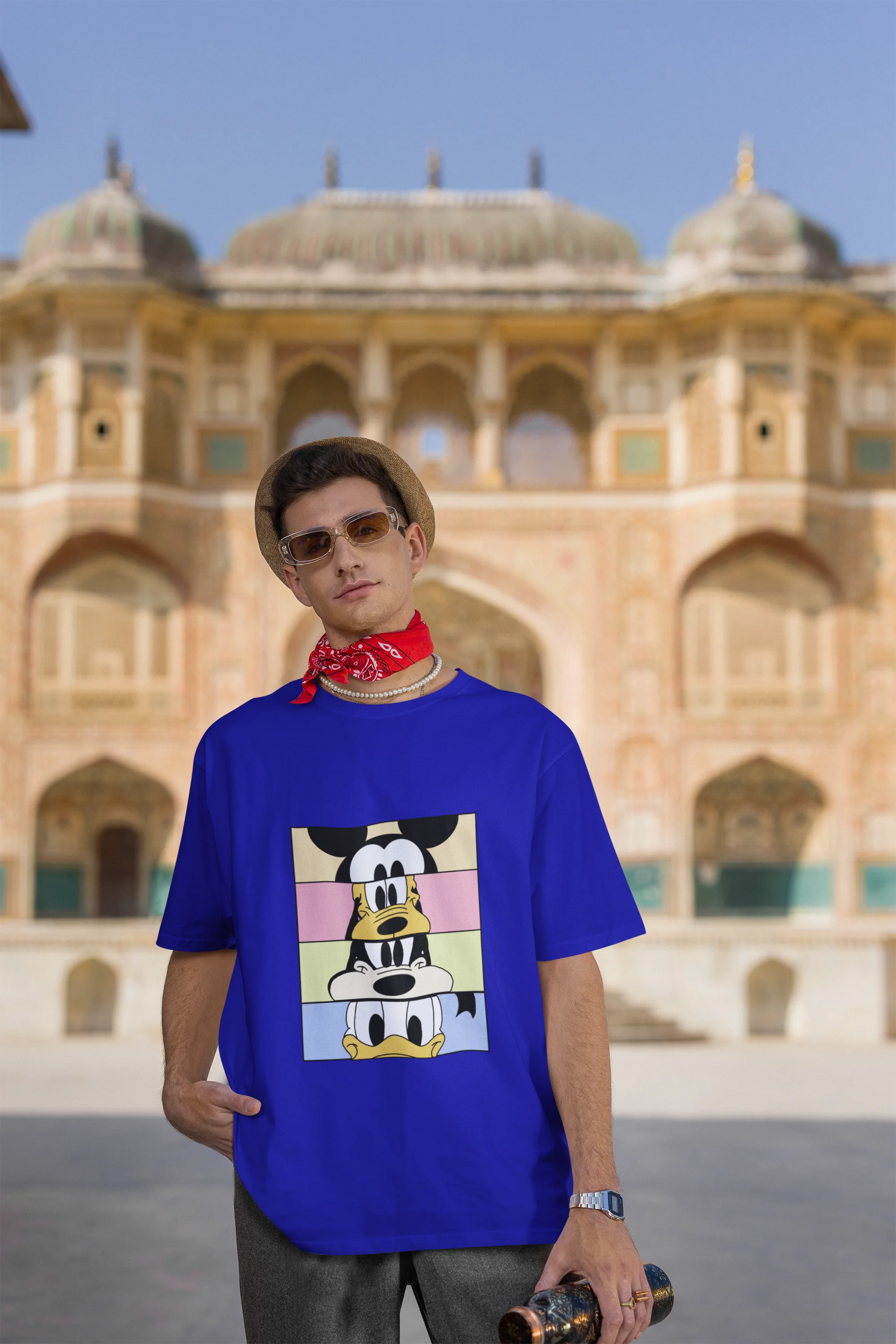 Third image of male Model showcasing blue oversized t-shirt inspired by Mickey Mouse Clubhouse characters: Mickey Mouse, Donald Duck, Goofy, and Minnie Mouse